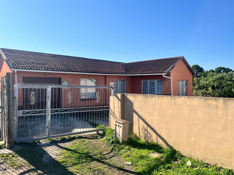 Front view of a single-story house featuring a tiled roof, metal security gate, perimeter wall, and a garage.