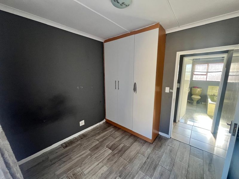 A bedroom featuring wood-look tiled flooring, a built-in wardrobe, and direct access to an adjoining bathroom.
