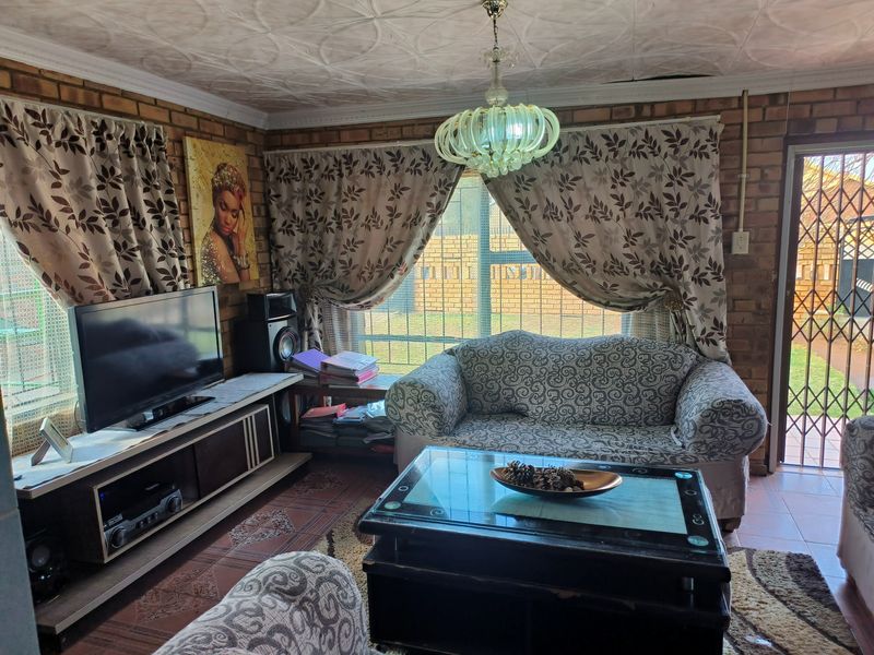 Living room featuring exposed brick walls, patterned ceiling tiles, and tiled flooring, with direct access to the exterior through a security gate.