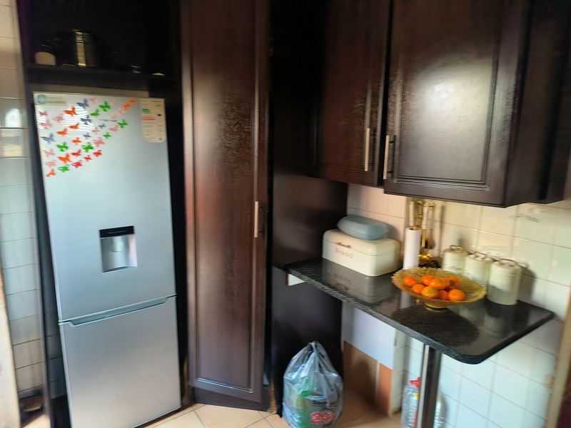 A compact kitchen area featuring dark wood cabinetry, granite countertops, and a tiled backsplash, providing functional storage and preparation space.