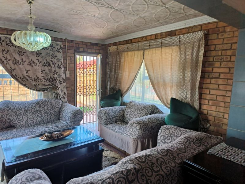 Living room featuring exposed brick walls, decorative ceiling tiles, and a security gate leading to the exterior.
