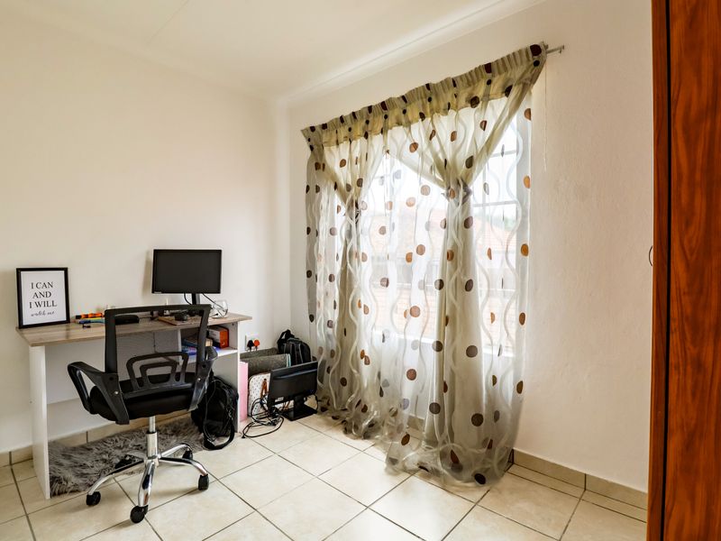 A bedroom featuring tiled flooring and a built-in cupboard, currently utilized as a home office space.