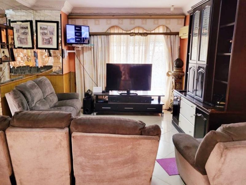 A living room featuring tiled flooring, mirrored wall accents, and decorative ceiling cornicing, providing a functional space with integrated air conditioning.
