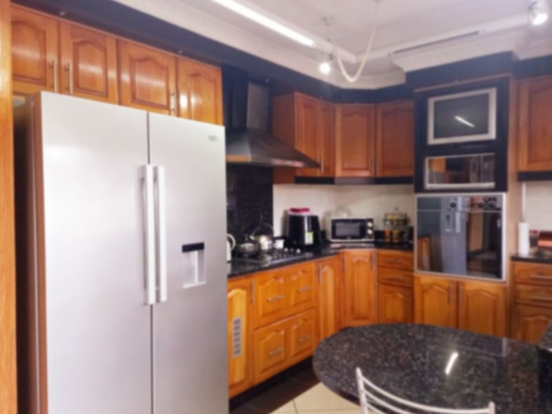 A kitchen featuring wooden cabinetry, granite countertops, and built-in appliances including an oven, microwave, and extractor fan.