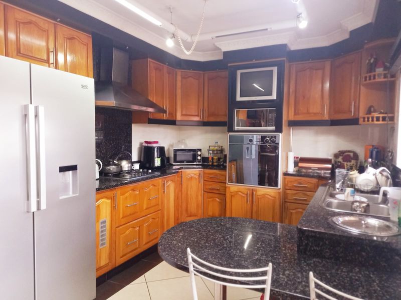 A functional kitchen featuring warm wooden cabinetry, granite countertops, built-in oven, extractor fan, and a breakfast nook area.