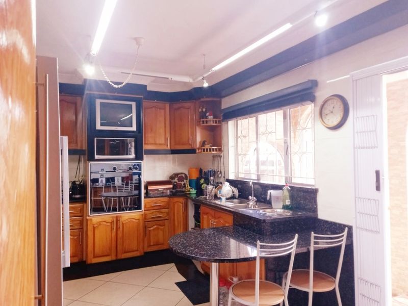 A functional kitchen featuring wooden cabinetry, granite countertops, built-in oven and microwave, and tiled flooring with a breakfast nook area.