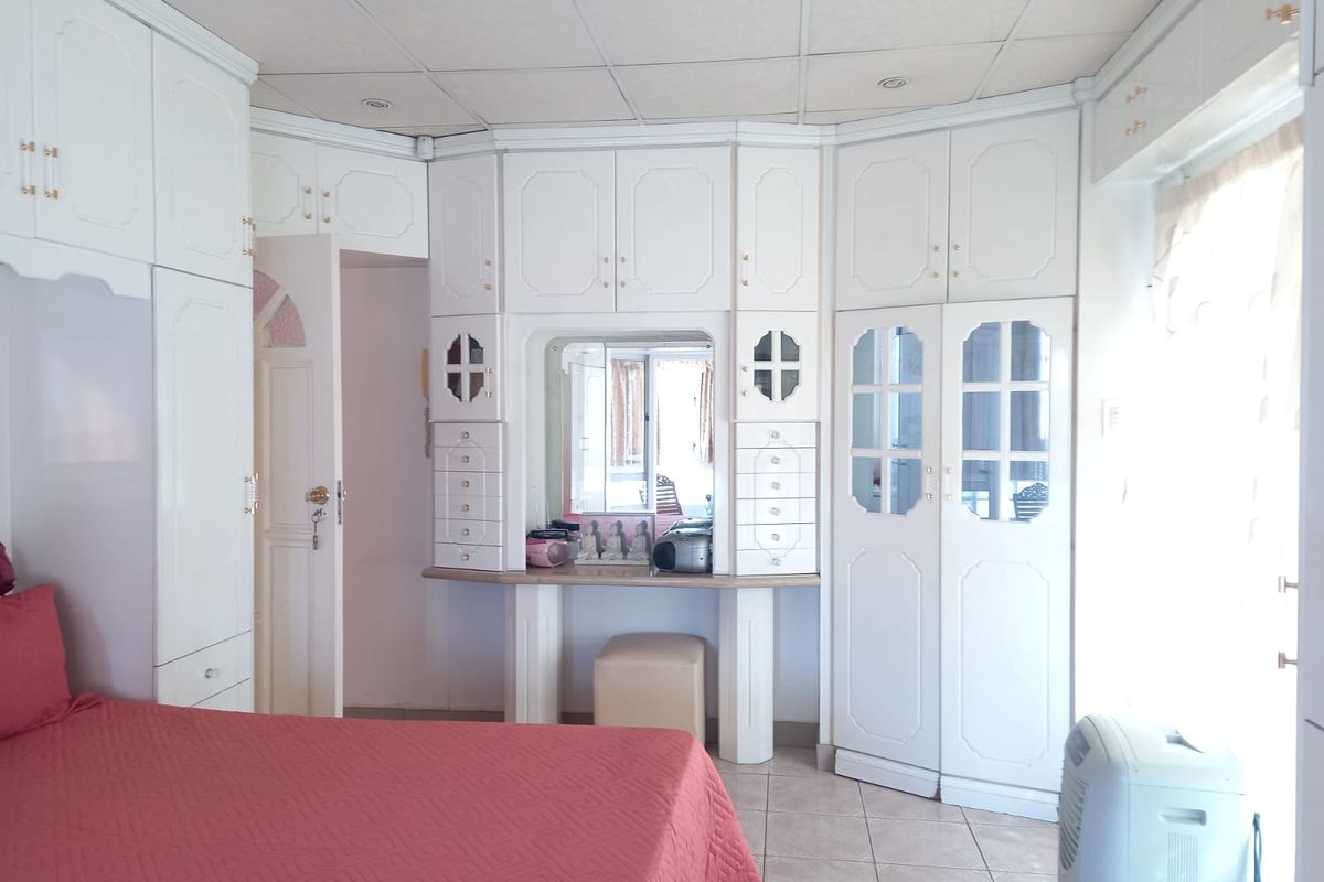 Bedroom featuring extensive white built-in cabinetry, a central vanity area, tiled flooring, and a drop ceiling.