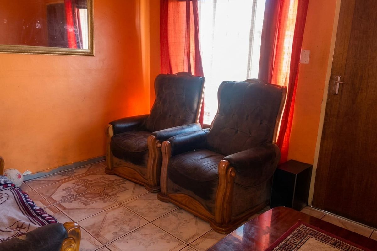 A living room area featuring tiled flooring and a wooden door, providing a functional space for relaxation.