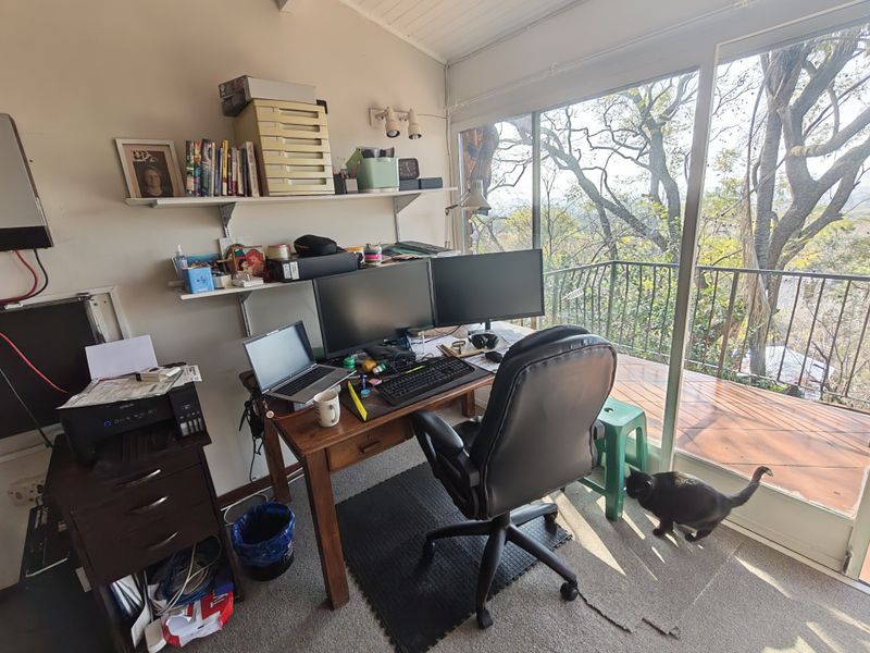A home office space featuring wall-mounted shelving and large sliding glass doors that open onto a balcony with scenic views.