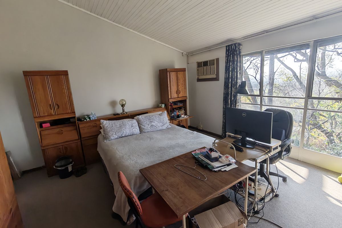 A bedroom featuring built-in wooden cabinetry, a window-mounted air conditioning unit, and large sliding glass doors providing natural light and outdoor views.