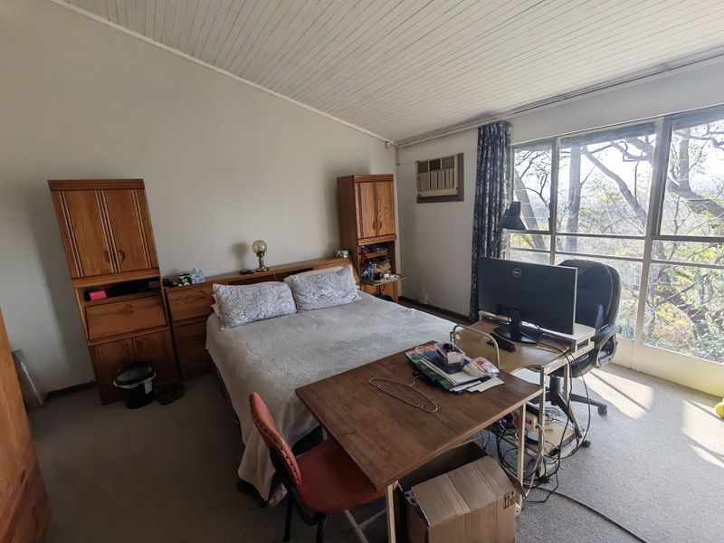 A bedroom featuring built-in wooden cabinetry, a window-mounted air conditioning unit, and large sliding glass doors providing natural light and outdoor views.