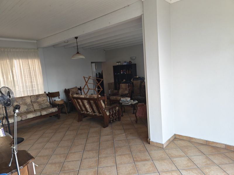 A spacious living area featuring tiled flooring and an exposed beam ceiling, offering a functional layout with ample natural light.