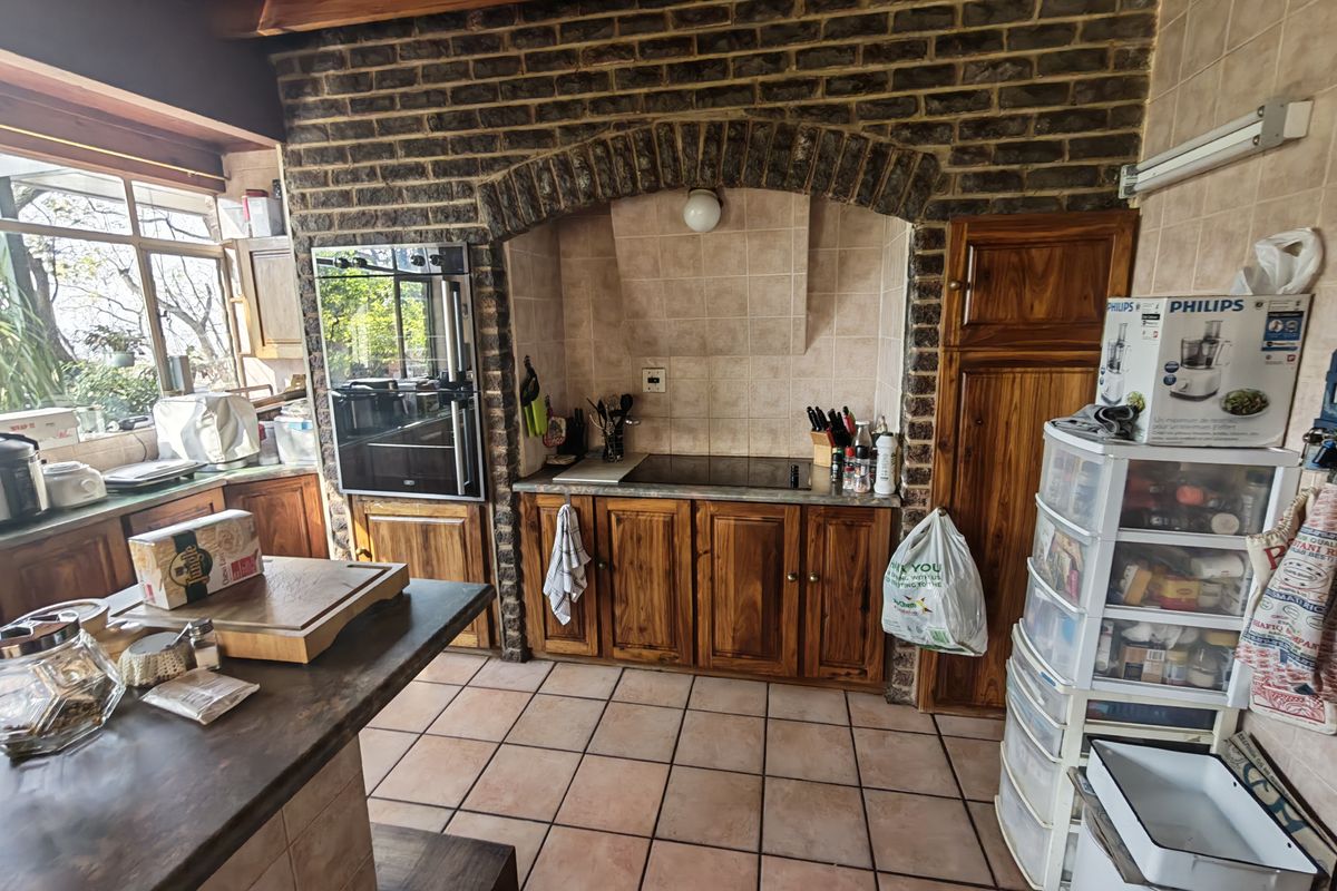 A rustic kitchen featuring exposed brickwork, timber cabinetry, tiled flooring, and built-in cooking appliances, offering a warm and traditional aesthetic.