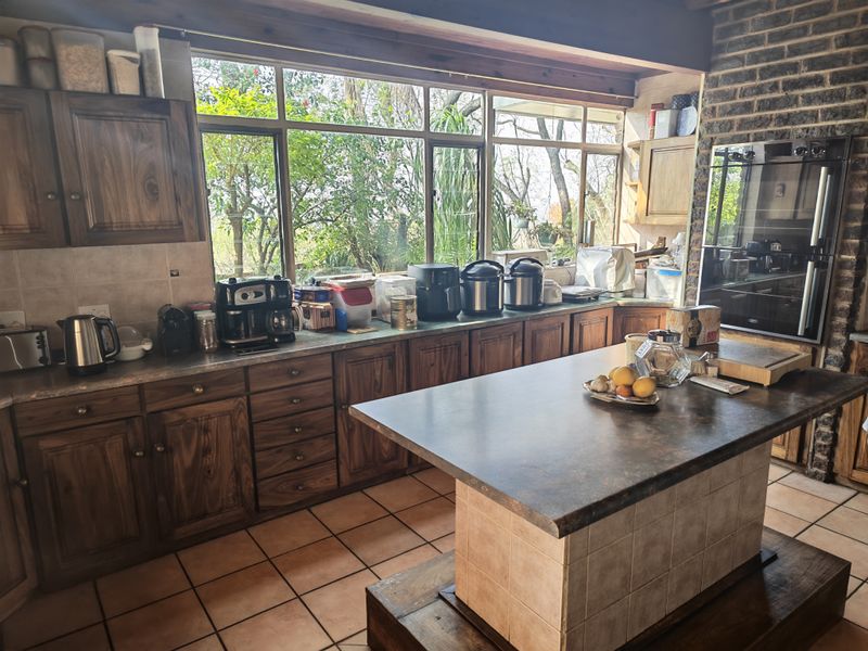 Spacious kitchen featuring traditional wooden cabinetry, a central island, tiled flooring, and an exposed brick wall with a built-in oven.