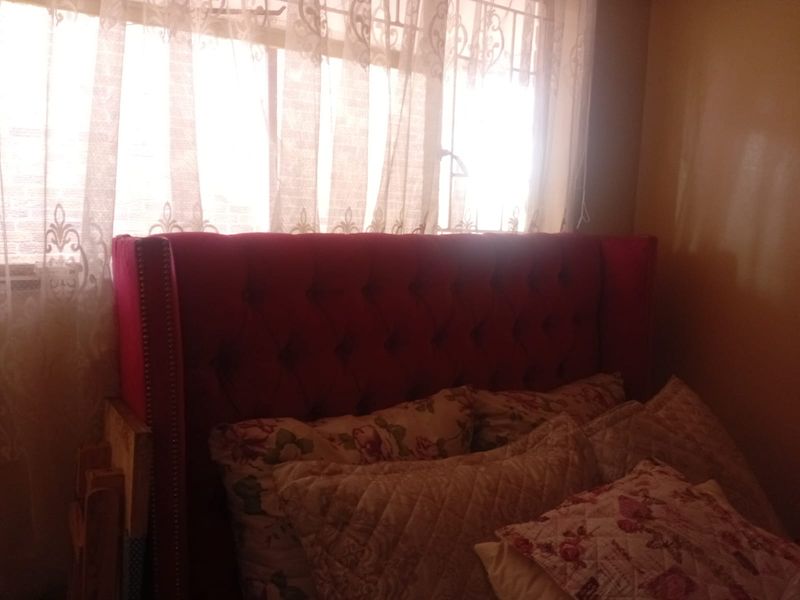 A bedroom interior featuring a window with security bars and natural light.