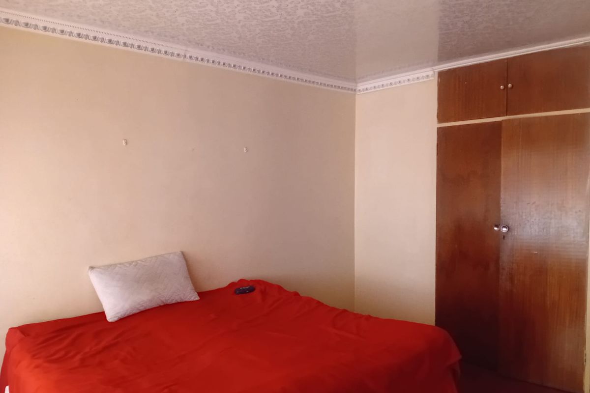 A bedroom featuring a built-in wooden wardrobe, textured ceiling, and decorative cornice detailing.