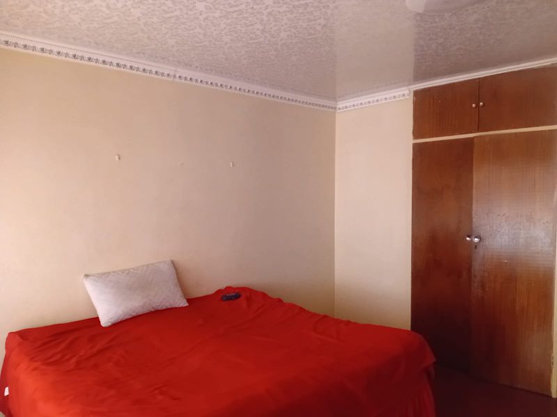 A bedroom featuring a built-in wooden wardrobe, textured ceiling, and decorative cornice detailing.