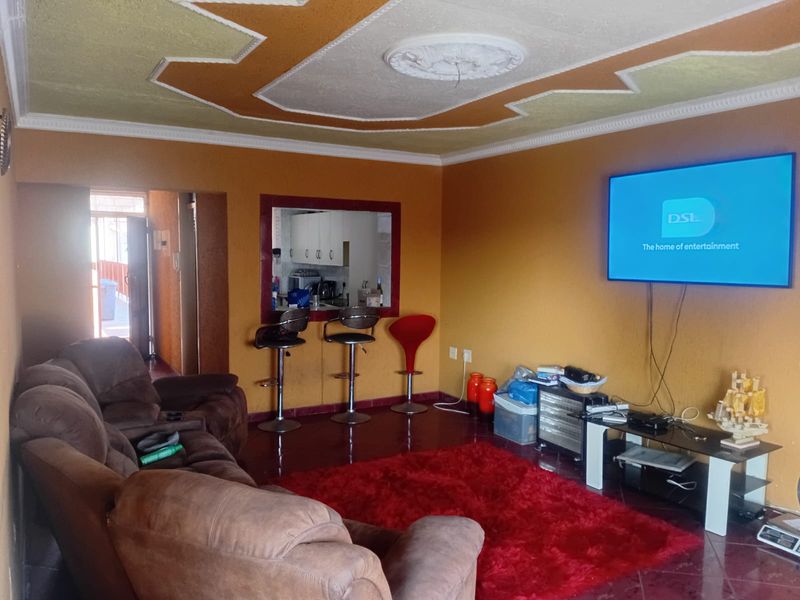 Open plan living area featuring a serving hatch to the kitchen, decorative ceiling details, and tiled flooring.