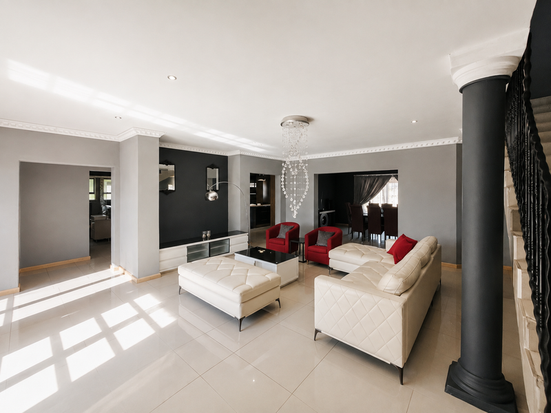 Spacious open-plan living area featuring modern porcelain tiling, decorative crown molding, recessed lighting, and a striking architectural column with an integrated staircase.