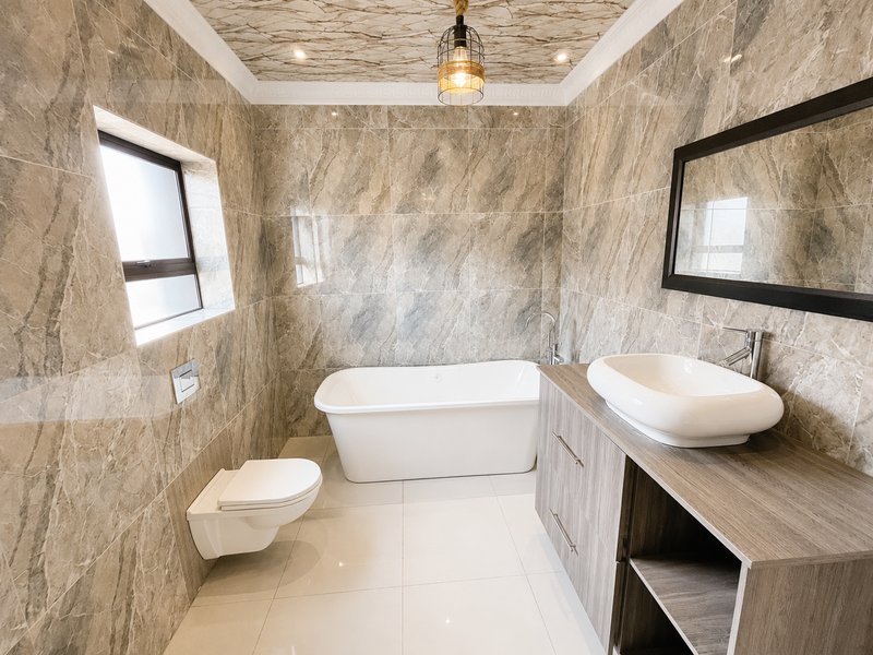 Modern bathroom featuring floor-to-ceiling marble-effect tiling, a sleek freestanding bathtub, wall-mounted toilet, and a contemporary vanity with a vessel sink.