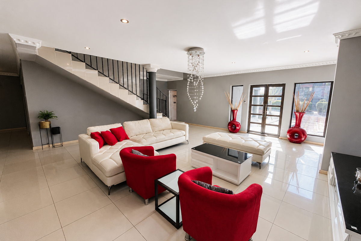 Spacious open-plan living area featuring polished porcelain tiles, a modern staircase with wrought iron balustrade, and elegant crystal chandelier lighting.
