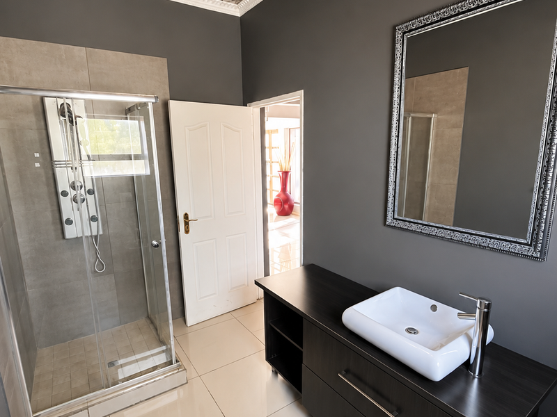 Modern bathroom featuring a glass shower enclosure, dark wood vanity with a vessel sink, and decorative ceiling finish.
