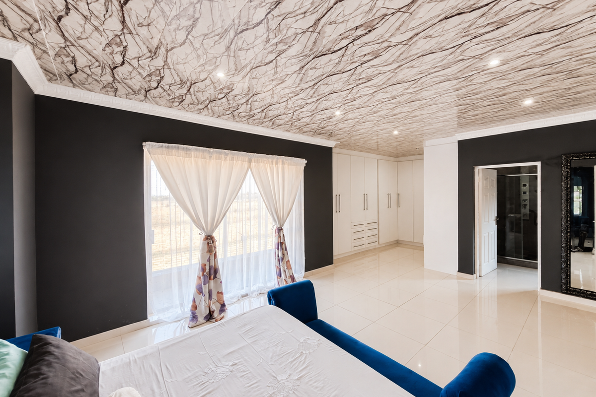 Spacious bedroom featuring modern dark accent walls, a unique marble-effect ceiling, built-in cabinetry, and large sliding doors leading to the exterior.