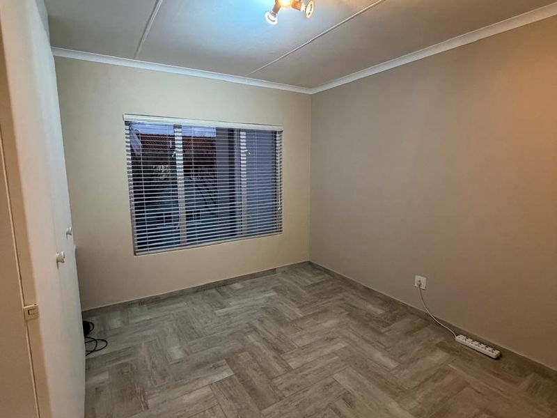 A clean, empty bedroom featuring modern herringbone tile flooring, a built-in cupboard, and neutral wall tones, ready for personalization.
