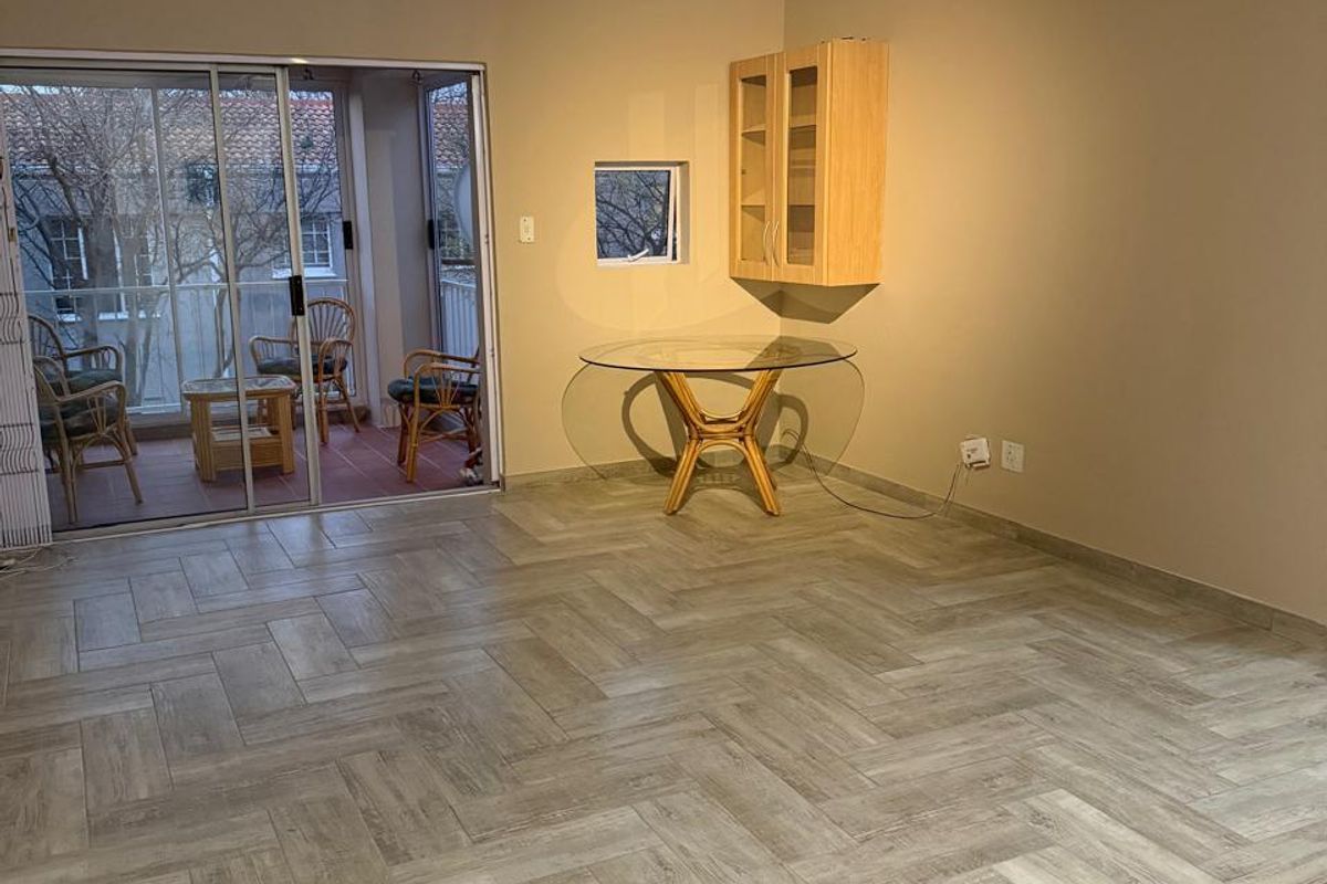Spacious living area featuring modern herringbone tile flooring, a ceiling fan, and sliding glass doors leading to an attached balcony.