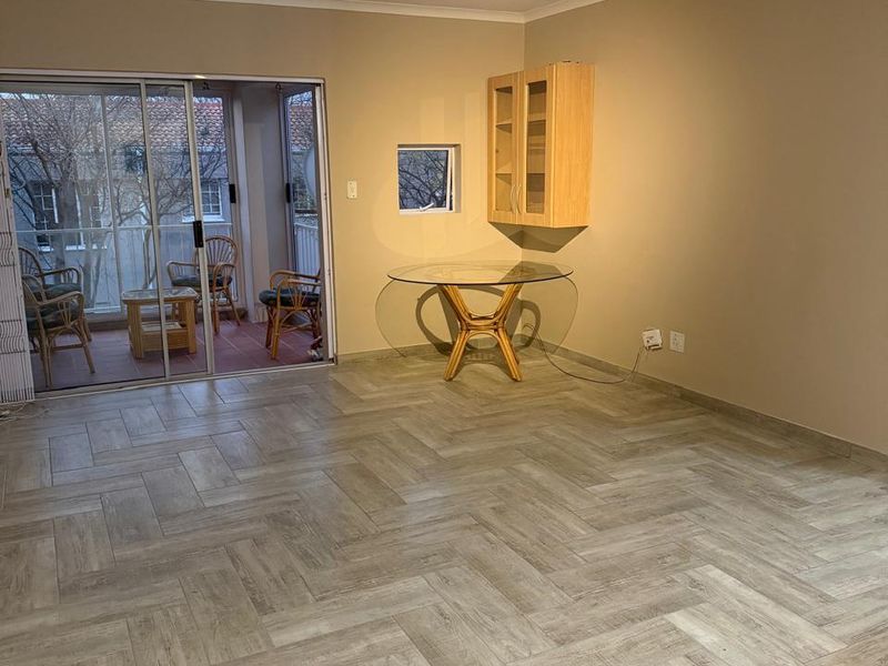 Spacious living area featuring modern herringbone tile flooring, a ceiling fan, and sliding glass doors leading to an attached balcony.