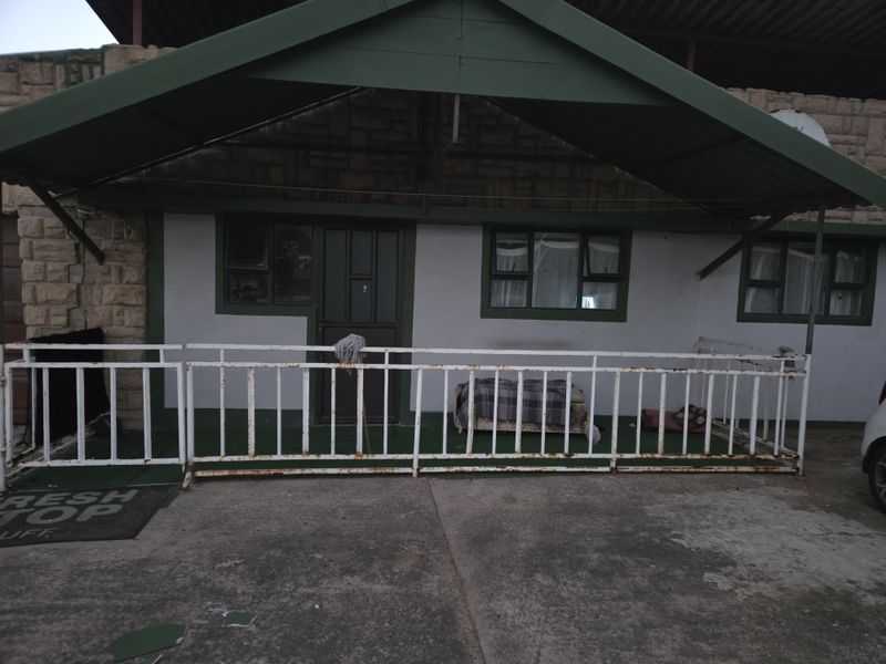 Front exterior view of the apartment featuring a covered entrance area with a metal canopy, security railing, and stone facade detailing.