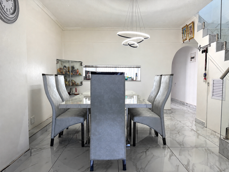 A bright dining area featuring polished marble-look floor tiles, a contemporary LED pendant light, and an elegant archway leading to adjacent living spaces.