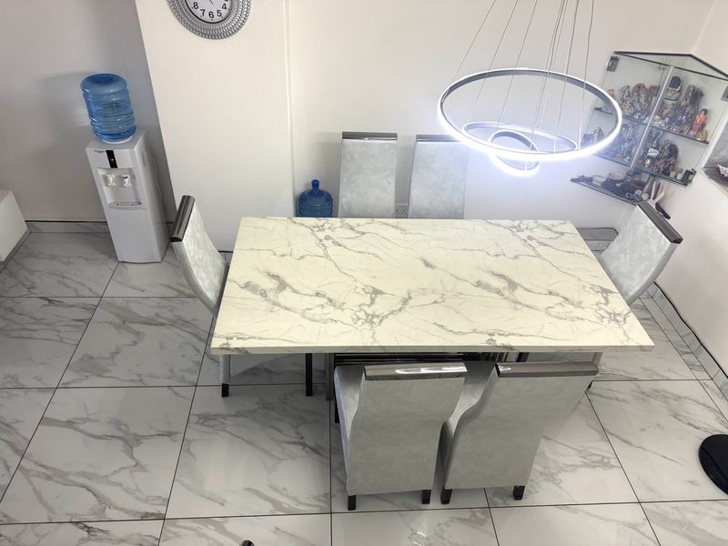A bright dining area featuring large-format marble-look porcelain floor tiles and a contemporary circular LED pendant light fixture.