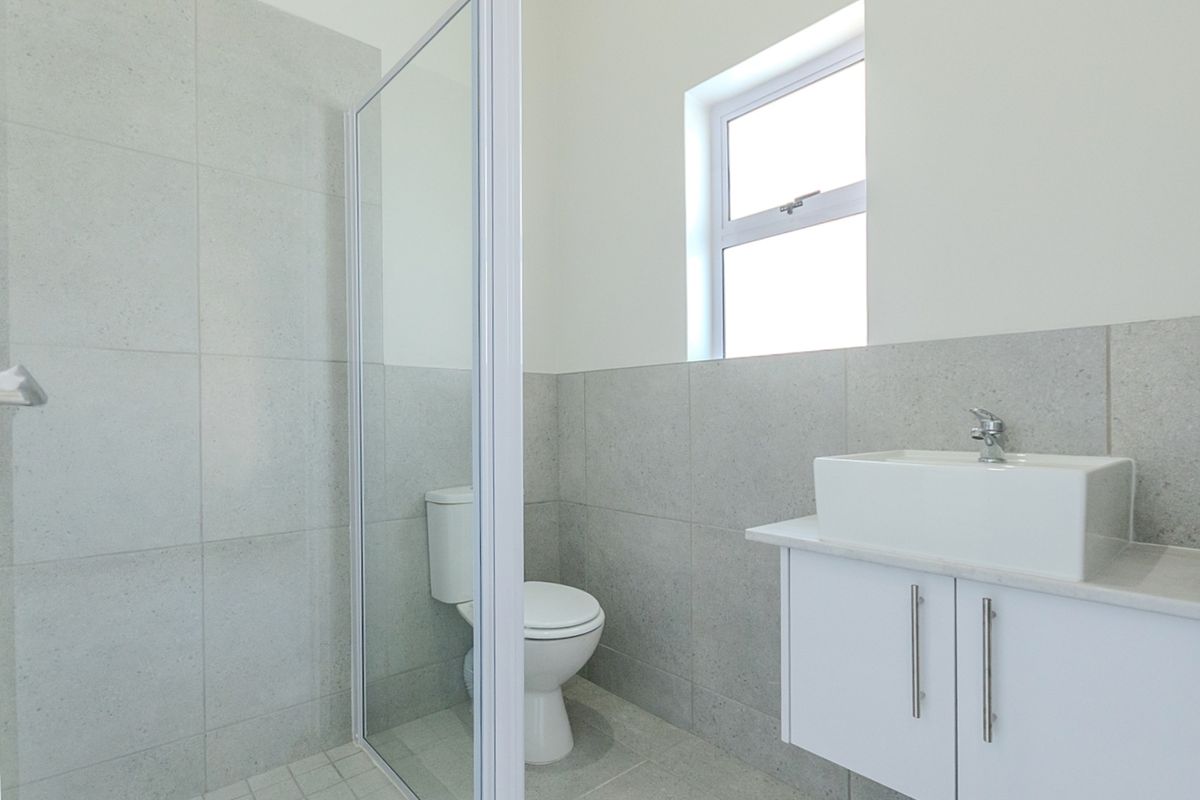 Modern bathroom featuring a glass shower enclosure, wall-mounted vanity with basin, and neutral tiled finishes.