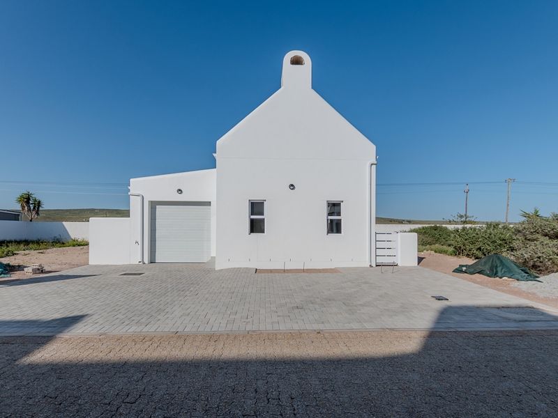 A clean, modern white house exterior featuring a paved driveway, integrated garage, and a prominent chimney against a clear blue sky.