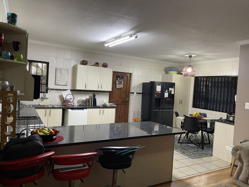 Open plan kitchen and dining area featuring granite countertops, ample built-in cabinetry, and tiled flooring, offering a functional layout for daily living.