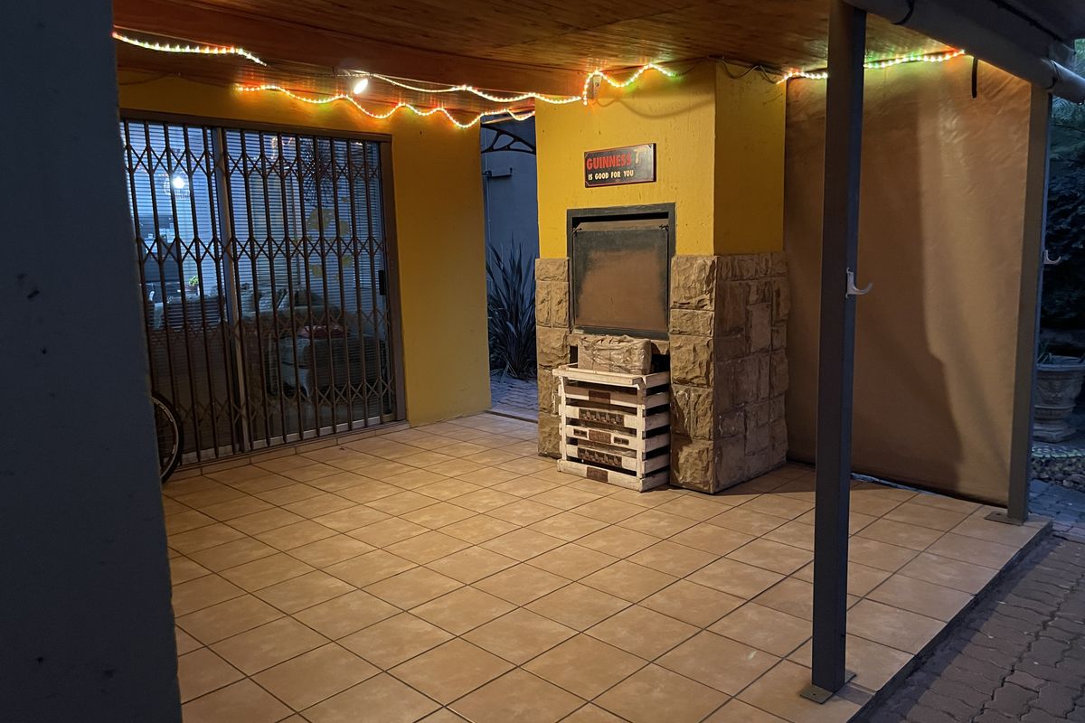 Covered patio area featuring a built-in braai, tiled flooring, and timber ceiling, providing a functional outdoor entertainment space.