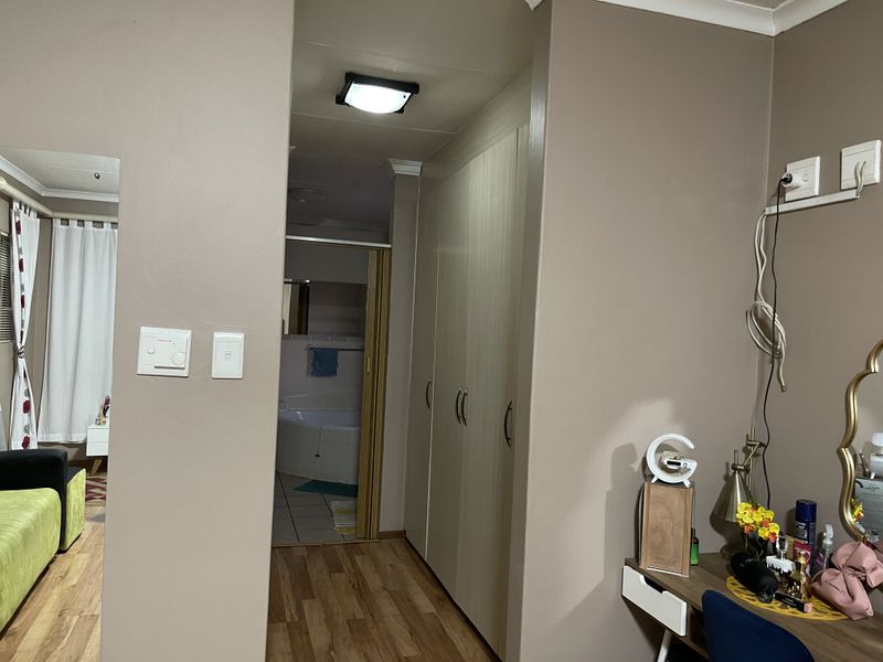 Bedroom featuring built-in cupboards, laminate flooring, and direct access to an en-suite bathroom.