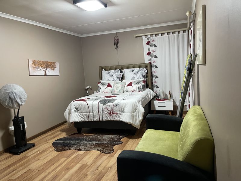 A well-maintained bedroom featuring laminate flooring and neutral wall tones, providing a comfortable and functional living space.