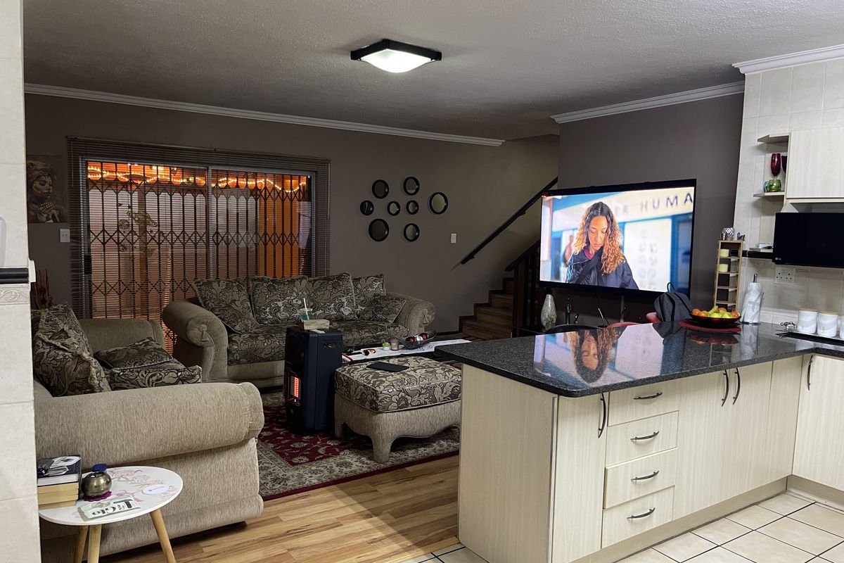 Open plan living area featuring a kitchen island with granite countertops, tiled flooring, and a staircase leading to the upper level.