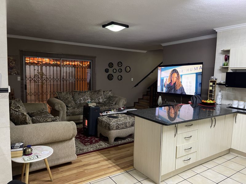Open plan living area featuring a kitchen island with granite countertops, tiled flooring, and a staircase leading to the upper level.