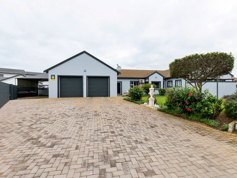 Front view of the property featuring a paved driveway, double garage, and well-maintained garden area.