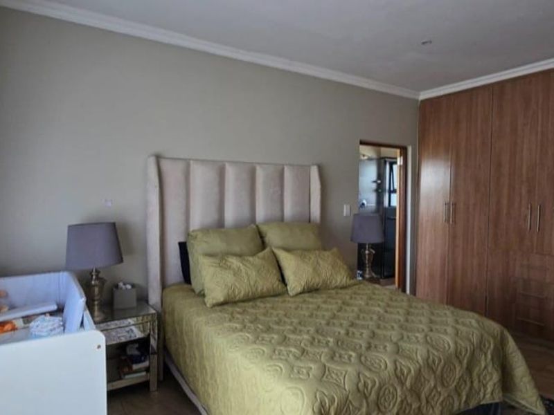 A well-maintained bedroom featuring extensive built-in wooden cupboards and laminate flooring, offering ample storage space and a neutral color palette.