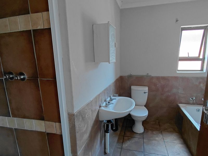 A functional bathroom featuring a shower, bathtub, toilet, and washbasin with neutral tiled finishes.