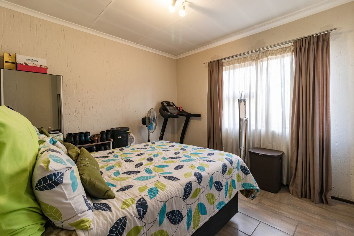 A bedroom featuring tiled flooring and natural light through a window with curtain rails.