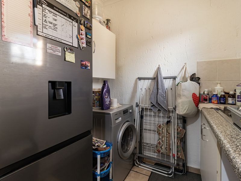 A functional laundry area featuring built-in cabinetry, a laminate countertop, and a stainless steel sink, providing practical utility space for household tasks.