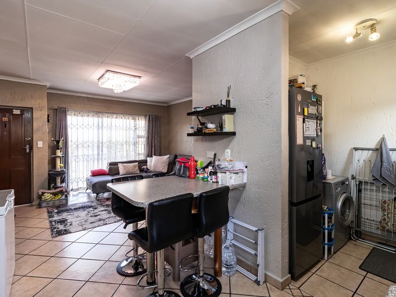 Open-plan living area featuring tiled flooring, a breakfast bar, and direct access to the patio through a security gate.