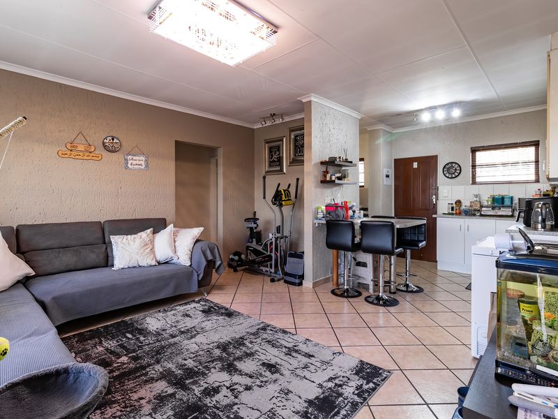 Open-plan living and kitchen area featuring tiled flooring, a breakfast bar, and functional cabinetry, offering a versatile space for daily living and dining.
