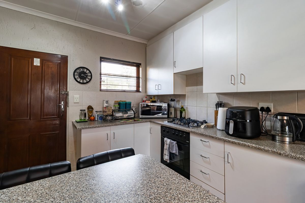 A functional kitchen featuring white cabinetry, granite countertops, a gas hob, and a built-in oven with tiled backsplash.