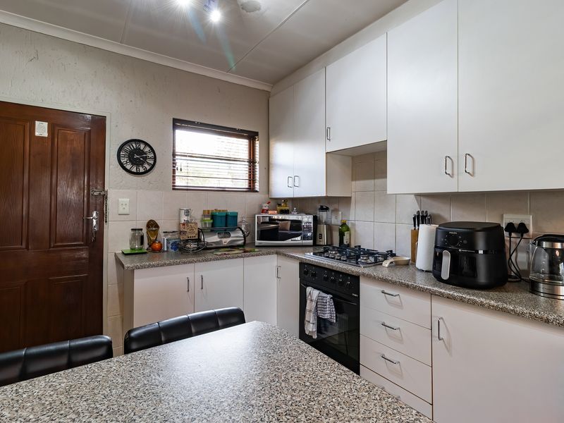 A functional kitchen featuring white cabinetry, granite countertops, a gas hob, and a built-in oven with tiled backsplash.
